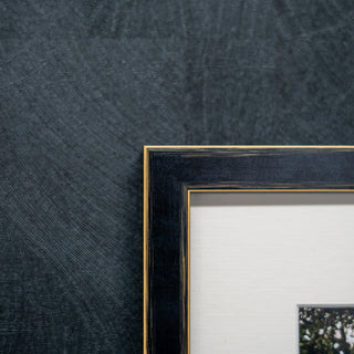 corner of a framed picture on a textured dark grey wall 
