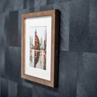 Framed picture on a textured grey wall with a wooden bronze frame