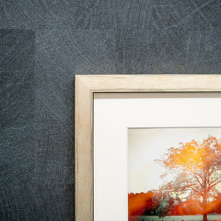 Framed artwork on a textured grey wall in a gold frame  