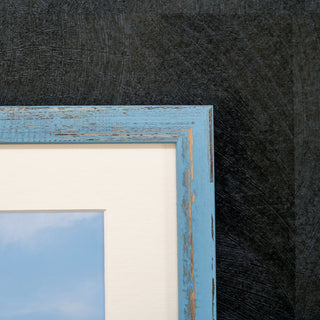 Close-up of a blue wooden picture frame corner on a textured black background