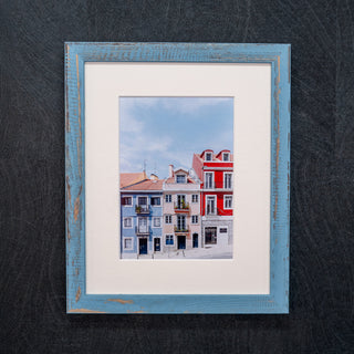 Framed photograph of colorful buildings against a blue sky.