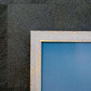 Wooden picture frame with peeling paint on a textured dark gray background