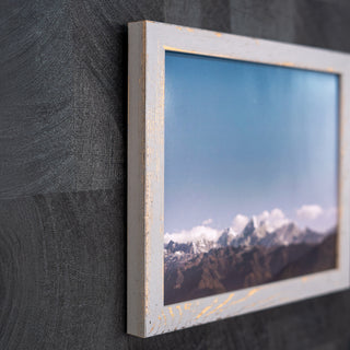 Framed photograph of a mountain landscape on a textured wall