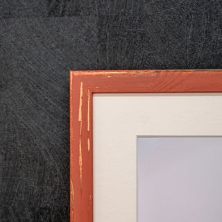 Close-up of a red wooden picture frame corner on a textured dark background