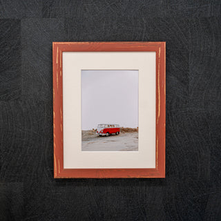 Framed photograph of a red van on a black textured background in a red wooden frame