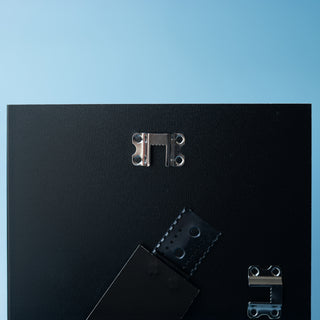 close up showing wall hanging fixings on the back of a picture frame back board on a blue background
