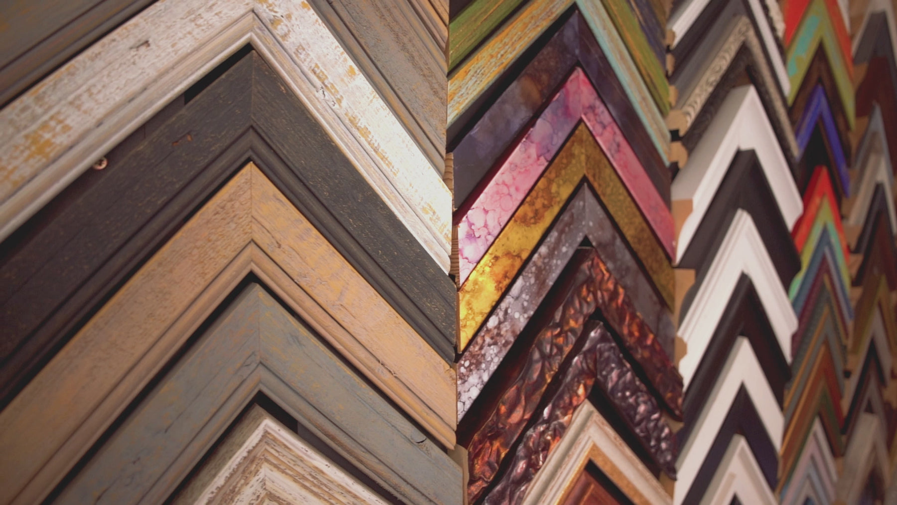 Slowly panning over a display wall of various wooden chevron picture frames. Ranging from woods to colourful, black and white and textured. 