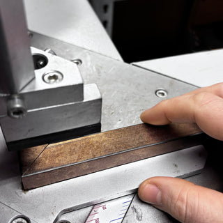 Close up of hand holding a bronze linea Frame X frame on an underpinner machine.
